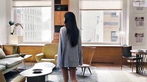 Brunette in short gray sweater dress stands from behind teasing legs in luxury apartment
