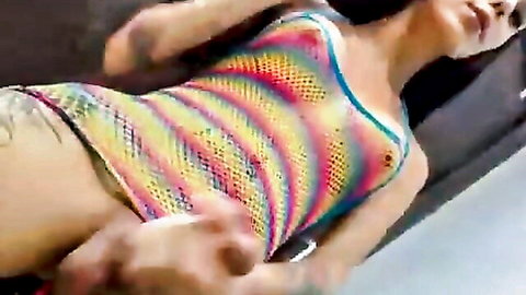 Trans woman in sheer rainbow mesh top gets handjob on hard cock lying on bed