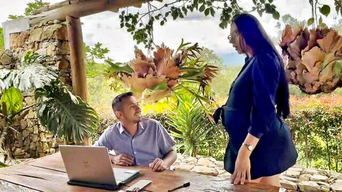 Pregnant Latina MILF in tight blue dress stands over seated man at outdoor desk
