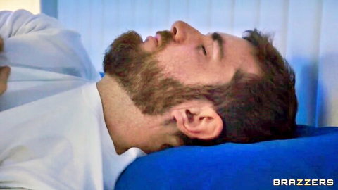 Bearded man lying relaxed on blue pillow in white shirt Brazzers scene