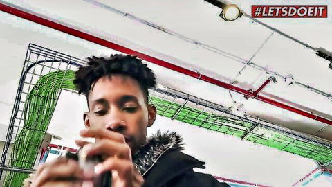 Black guy with dreads taking close-up selfie holding phone in industrial warehouse