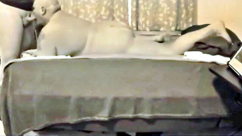 Nude couple in intimate bedroom pose, man lying back with woman on top