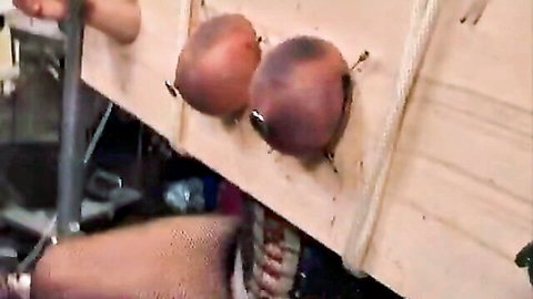 Bound exposed breasts in wooden fetish restraint, intense BDSM play