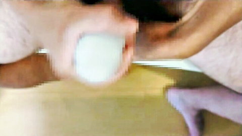 Blurry close-up of hands gripping white Tenga egg toy for masturbation