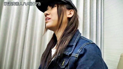 Asian woman in denim jacket and cap, long hair in ponytails, seductive side glance
