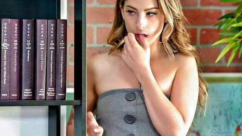 Seductive blonde in gray strapless dress biting finger teasingly