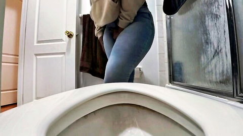 Curvy woman squirming in tight jeans, holding pee desperation in bathroom