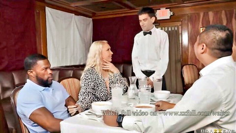 Busty blonde MILF in leopard dress teasing two black studs at restaurant table with waiter serving drinks