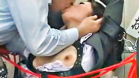 Japanese woman in BDSM harness kissed by man, breast exposed in hardcore scene