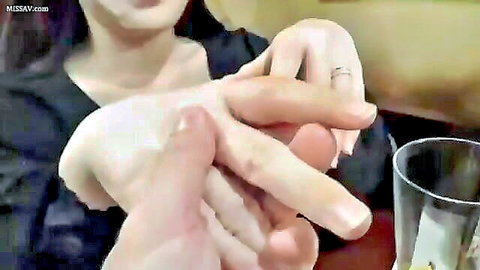 Asian woman in black top intimately intertwining fingers with partner