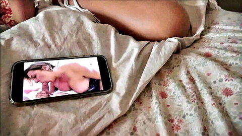 Busty topless MILF with huge tits displayed on smartphone screen lying on bed