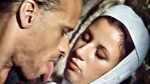 Bearded man passionately licks brunette woman's face under white veil in intense vintage encounter