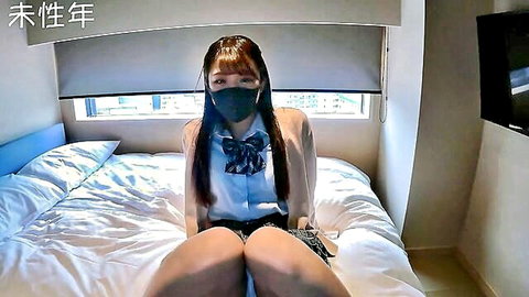 Petite Japanese student in school uniform sits on bed spreading thighs wide wearing face mask