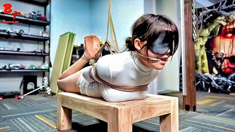 Blindfolded Asian woman in tight white outfit, bound in ropes hogtie position