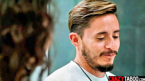 Handsome blonde bearded guy in white shirt gazes intimately at curly-haired woman close-up