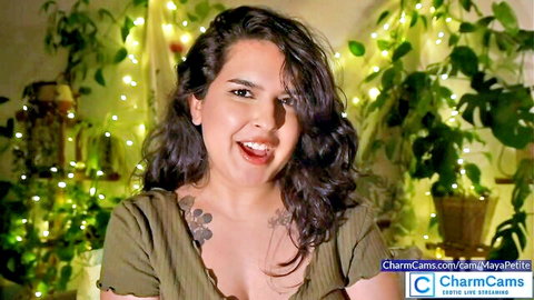 MayaPetite smiling teasingly in low-cut green top, showing tattoos on CharmCams
