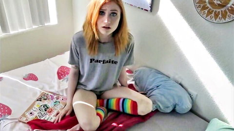 Surprised redhead in Parfait t-shirt and colorful thigh socks on bed, caught watching comics