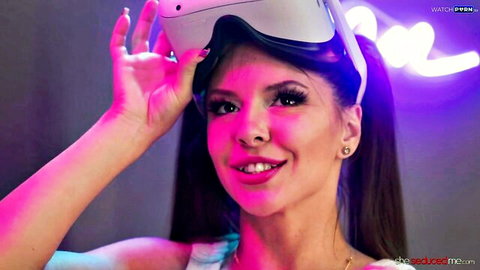 Seductive young brunette lifts VR headset smiling with perky small tits cleavage