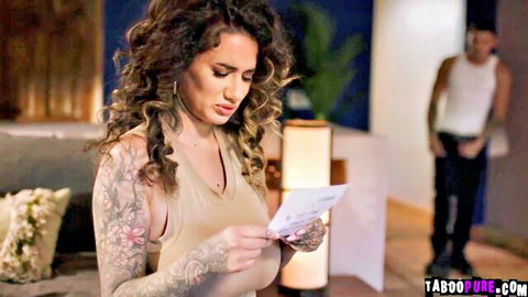 Tattooed curvy brunette MILF with huge natural tits reads letter while muscular guy watches from behind