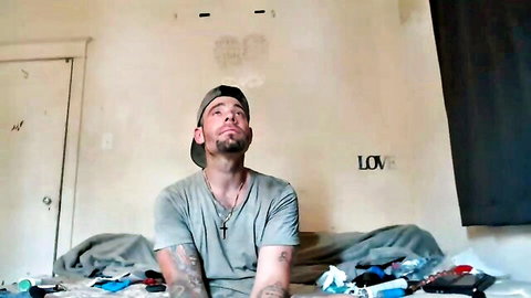 Tattooed man in cap stripping Bad Dragon style solo scene