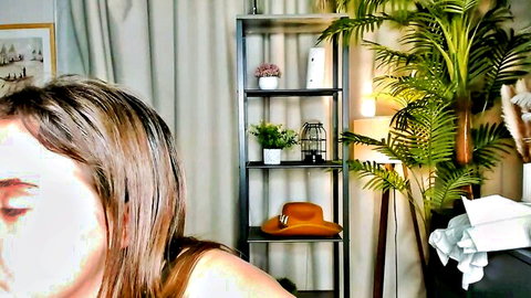 Webcam girl with sheet face mask in plant-filled room