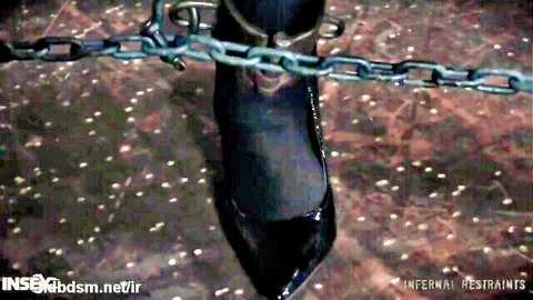 Woman in black high heels and stockings bound by chains in intense BDSM play