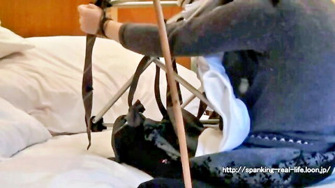 Bound Japanese woman in gray top and white bottoms for spanking fetish