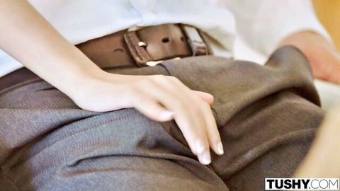 Slim woman in white blouse teasing man's bulge over gray pants