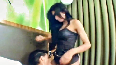 Brunette with big tits in shiny black top grips man's head between her thighs