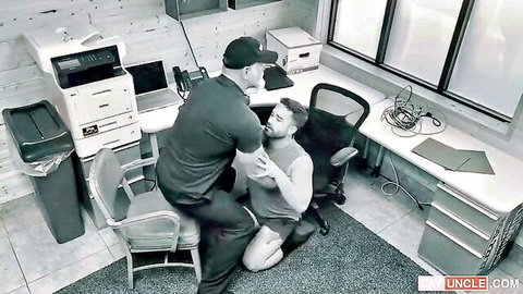 Muscular guy in cap grabs bearded shirtless hunk's arm in tense gay office domination