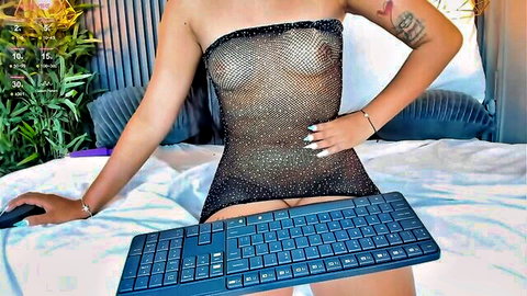 Thick tattooed babe in sheer sparkly dress exposes tits teasing pussy with keyboard on bed