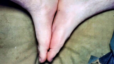 Close-up of hairy male bare soles and toes arched on couch for foot worship.