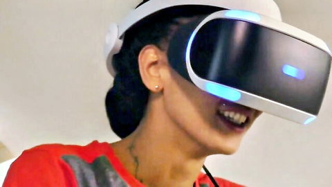 Smiling Asian woman in PlayStation VR headset, red top, neck tattoo