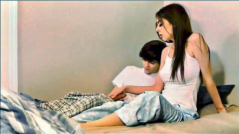 Petite brunette teen in tight white tank top and pajama pants cuddling with boyfriend on bed