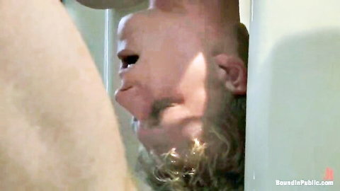 Bearded man gives upside-down blowjob through glory hole under bathroom stall wall