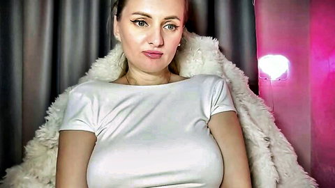 Busty MILF with huge natural tits in tight white top and fluffy fur jacket teasing cleavage on webcam