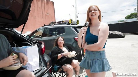 Harlow West in sexy denim skirt holds mic in parking lot pickup scene