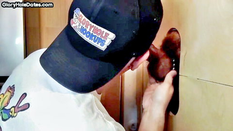 Capped guy strokes hairy cock through glory hole in amateur gay hookup.