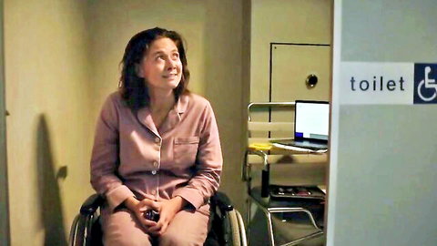 Bree Peters in pink pajamas, smiling in wheelchair from Spinal Destination nude scenes