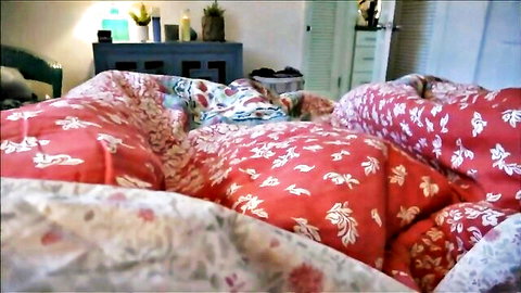 Brianna Beach lying on stomach in colorful bed quilts
