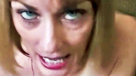 Seductive blonde woman with piercing blue eyes and red lips smirking intensely in close-up