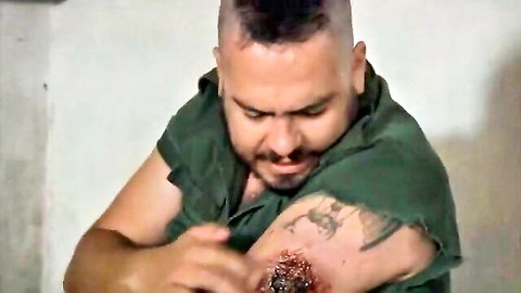Gisele Ferran & Raíssa Vitral in Zombio 2: Zombie with bloody arm wound in green shirt