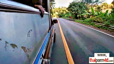 Hand hanging out bus window on scenic Thai rural road trip
