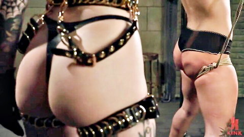 BDSM woman in black leather harness and chains, big ass exposed in punishment scene from Kink