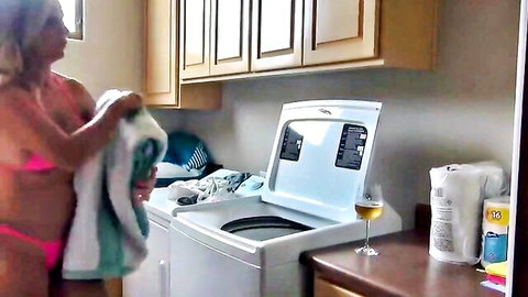 Busty topless blonde MILF in pink thong bending over open washing machine holding towel