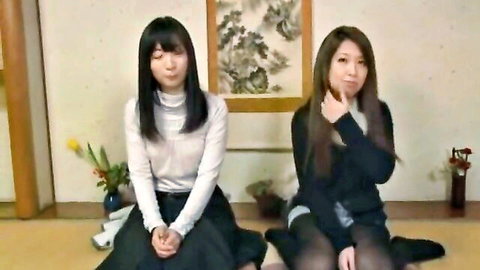 Two Japanese schoolgirls in uniforms sitting on tatami floor
