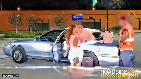Blonde stepmom in white dress and brunette stepdaughter flirt with mechanic by silver car roadside