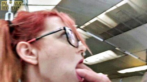 Redhead Joy in pigtails and glasses licks finger eagerly on train