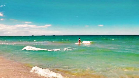 Topless skinny brunette babe with small ass wading nude in beach waves showing bare back