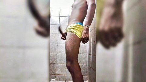 Tanned teen pulls down tight yellow briefs exposing hard cock base in steamy shower solo